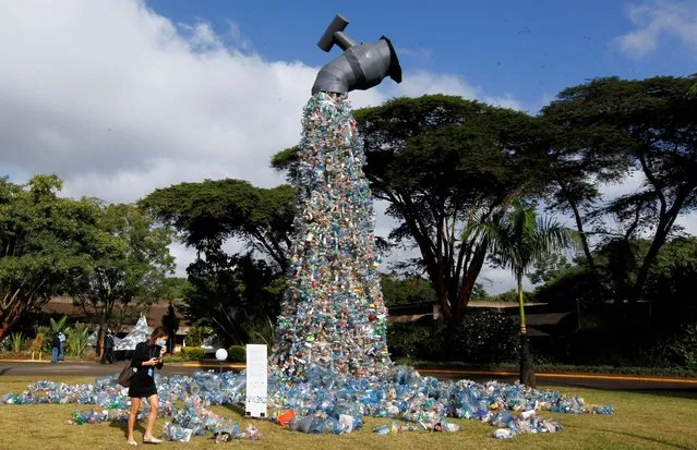 A delegate looks at a 30-foot monument dubbed “turn off the plastic tap” by Canadian activist and artist Benjamin von Wong, made with plastic waste collected from Kibera slums, at the venue of the Fifth Session of the United Nations Environment Assembly (UNEA-5), at the United Nations Environment Programme (UNEP) Headquarters in Gigiri, Nairobi, Kenya on February 28, 2022. (Photo by Monicah Mwangi/Reuters)