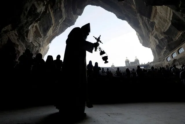 An Egyptian Coptic Orthodox Christian priest during a Palm Sunday mass at the Samaan el-Kharaz Monastery, in the Mokattam Mountain area of Cairo, Egypt, April 17, 2022. (Photo by Mohamed Abd El Ghany/Reuters)