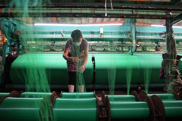A worker produces fiber netting at a factory in Binzhou in China's eastern Shandong province on May 31, 2022. (Photo by AFP Photo/China Stringer Network)