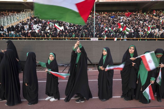 Young veiled schoolgirls are carrying Iranian flags as one of them is waving a Palestinian flag while participating in a gathering to support the mandatory hijab at the Azadi (Freedom) Stadium in western Tehran, Iran, on July 25, 2024. (Photo by Morteza Nikoubazl/NurPhoto/Rex Features/Shutterstock)