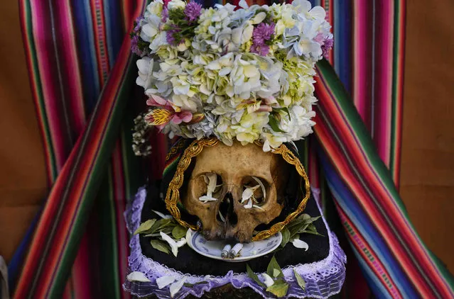 A decorated human skull sits on display at the General Cemetery during the annual “Natitas” festival, a local tradition marking the end of the Catholic All Saints holiday in La Paz, Bolivia, Monday, November 8, 2021. The “Natitas”, which means “without a nose” in the Indigenous Aymara language, are cared for and decorated by faithful who use them as amulets for protection.. (Photo by Juan Karita/AP Photo)