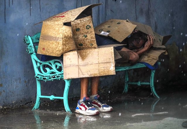People at a bus stop shield themselves with cardboard amid wind and rain during the passage of Hurricane Rafael in Havana, Cuba, Wednesday, November 6, 2024. (Photo by Ramon Espinosa/AP Photo)