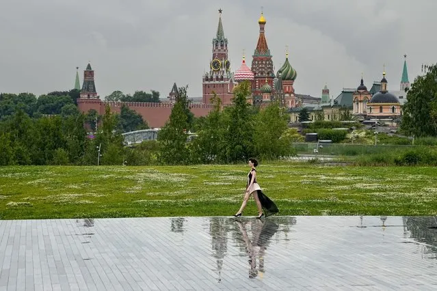 A model displays a collection by a group of Russian designers of the Moscow Art-Industrial Institute, during the Fashion Week at Zaryadye Park with the Spasskaya Tower and St. Basil's Cathedral in the background near Red Square in Moscow, Russia, Tuesday, June 21, 2022. (Photo by Alexander Zemlianichenko/AP Photo)