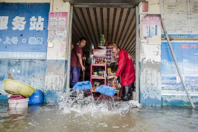 People clear water from a house in flooded Zhangji village in Maliang, China on July 21, 2016. Heavy rain since Tuesday has caused flooding throughout China. (Photo by Xinhua/Barcroft Images)