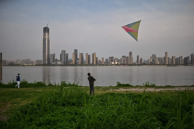 In this photo taken on April 8, 2020, a man wearing a face mask flies a kite along the Yangtze River in Wuhan, China's central Hubei province. Thousands of Chinese travellers rushed to leave COVID-19 coronavirus-ravaged Wuhan on April 8 as authorities lifted a more than two-month prohibition on outbound travel from the city where the global pandemic first emerged. (Photo by Hector Retamal/AFP Photo)