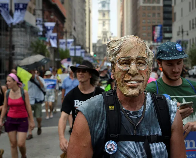 A protester wearing a mask depicting Senator Bernie Sanders marches down Broad Street during the Democratic National Convention in Philadelphia, Pennsylvania, U.S., July 25, 2016. (Photo by Bryan Woolston/Reuters)