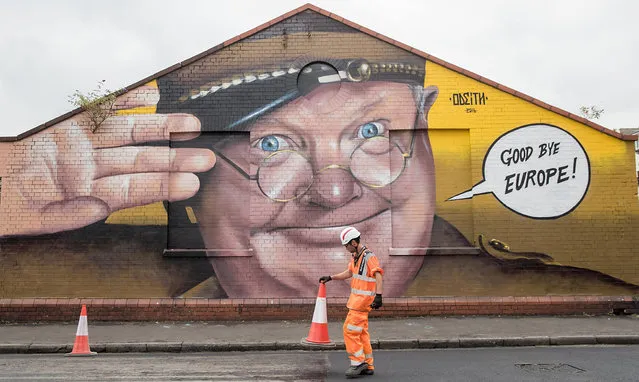 A construction worker moves a traffic cone in front of artwork by Odeith and is part of the 2016 Upfest on July 27, 2016 in Bristol, England. The annual event, which this year helped celebrate 45 years of the Mr Men and Little Miss book series, started in 2008 and is said to be the largest free street art and graffiti festival in Europe. The festival now attracts more than 300 artists including Inkie, Jody, Pichi & Avo and Leon Keer from 25 countries to paint live on walls and surfaces around Bedminster and Southville areas of the city of Bristol, the hometown of guerrilla artist Banksy. (Photo by Matt Cardy/Getty Images)