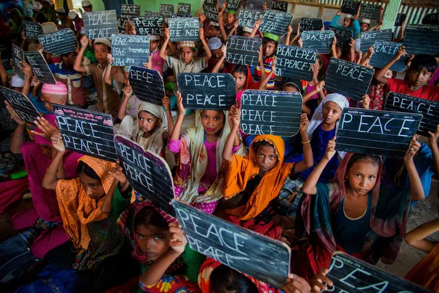 A group of Rohingya children who fled from oppression in Myanmar, are seen inside a Madrasah showing black boards prepared by them written “Peace”, at Leda camp in Coxs Bazar, Bangladesh on October 11, 2017. (Photo by Stringer/Anadolu Agency/Getty Images)