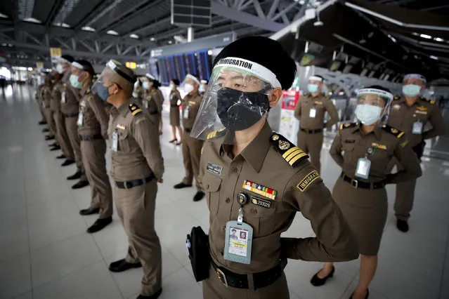 Thai immigration officials wearing protective masks and visors line up at the start of their shift at Suvarnabhumi International airport in Bangkok, Thailand, 04 May 2020. Some airlines have resumed domestic flights after the Thai government eased restrictions that were imposed to curb the ongoing COVID-19 coronavirus pandemic following a drop in the number of deadly disease infections in Thailand, while the state of emergency decree and curfew will remain for another month until the end of May. (Photo by Diego Azubel/EPA/EFE/Rex Features/Shutterstock)