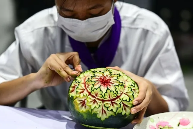 A Thai participant carves patterns into a watermelon during a fruit and vegetable carving competition at the 26th Thailand International Culinary Cup in Bangkok on September 21, 2022. (Photo by Manan Vatsyayana/AFP Photo)