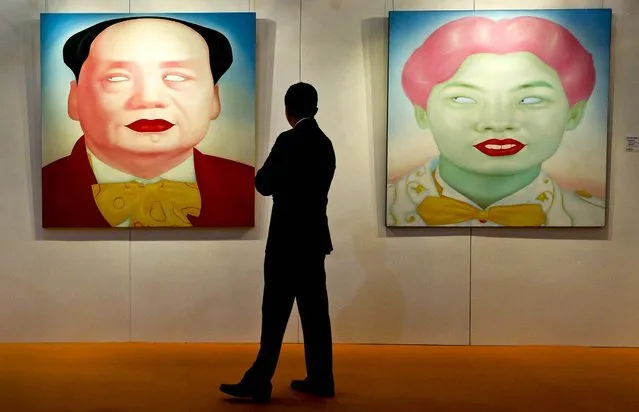 A man looks at two paintings “Mao”, and “Chinese Portrait Series No. 12” by Chinese artist Feng Zhengjie during Sotheby's auction press preview in Hong Kong, on October 4, 2012. The paintings are estimated to bring between $32,300 and $45,200. (Photo by Vincent Yu/Associated Press)
