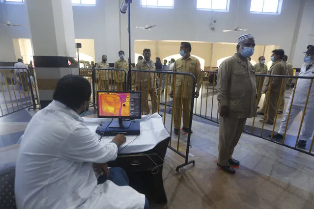 A railway officer checks the body temperature of staff ahead of the resumption of railway service after the government relaxed a weeks-long lockdown that was enforced to help curb the spread of the coronavirus, in Lahore, Pakistan, Tuesday, May 19, 2020. (Photo by K.M. Chaudhary/AP Photo)