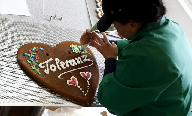 A woman decorates a gingerbread Oktoberfest heart with icing at the Fesey company factory in Munich, Germany September 15, 2015. Fesey will produce about 1000 gingerbread hearts with the word “tolerance” for the upcoming Oktoberfest. The proceeds will go toward the Caritas charity organisation. (Photo by Michaela Rehle/Reuters)