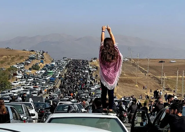 This UGC image posted on Twitter reportedly on October 26, 2022 shows an unveiled woman standing on top of a vehicle as thousands make their way towards Aichi cemetery in Saqez, Mahsa Amini's home town in the western Iranian province of Kurdistan, to mark 40 days since her death, defying heightened security measures as part of a bloody crackdown on women-led protests. A wave of unrest has rocked Iran since 22-year-old Amini died on September 16 following her arrest by the morality police in Tehran for allegedly breaching the country's strict rules on hijab headscarves and modest clothing. (Photo by UGC/AFP Photo)