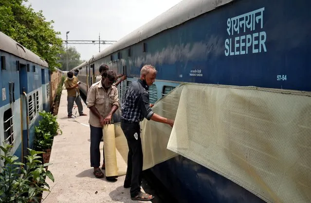 Workers fix mosquito net on a parked passenger train that will be equipped for the care of coronavirus disease (COVID-19) patients amidst the spread of the disease, at a railway yard in Ahmedabad, India, June 16, 2020. (Photo by Amit Dave/Reuters)