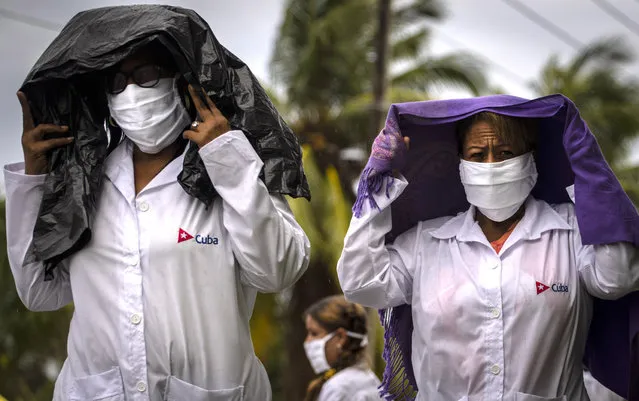 Health professionals who volunteered to travel to Kuwait to treat of coronavirus patients walk in the rain after attending their farewell ceremony in Havana, Cuba, Thursday, June 4, 2020. (Photo by Ramon Espinosa/AP Photo)