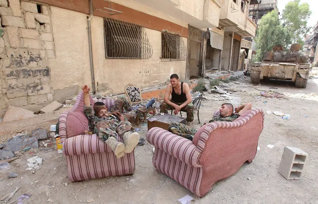 Syrian army soldiers rest in a street in the government-controlled part of the besieged town of Daraya on August 26, 2016, as thousands of rebel fighters and civilians prepared to evacuate under an accord struck a day earlier. An estimated 8,000 people remain in the town, despite a government siege lasting four years and regular regime bombardment. (Photo by Youssef Karwashan/AFP Photo)