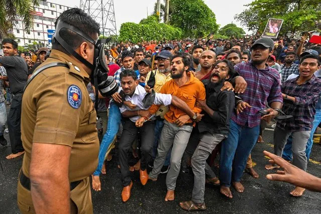 A policeman stands guard as protestors take part in an anti-government demonstration by the university students demanding the release of their leaders, in Colombo on October 18, 2022. (Photo by Ishara S. Kodikara/AFP Photo)
