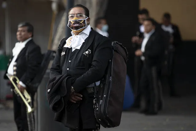 Mariachis, some wearing protective face  masks, wait for clients in Plaza Garibaldi, where residents come to hire mariachis for events and parties, in Mexico City, Friday, July 17, 2020. With large gatherings cancelled and concerns over singing inside closed spaces, work has plummeted for the hundreds of Mariachis based in Plaza Garibaldi. Those lucky enough to get occasional work say they are playing for small celebrations at home, such as birthdays or proposals, as well as at wakes for the deceased. (Photo by Rebecca Blackwell/AP Photo)