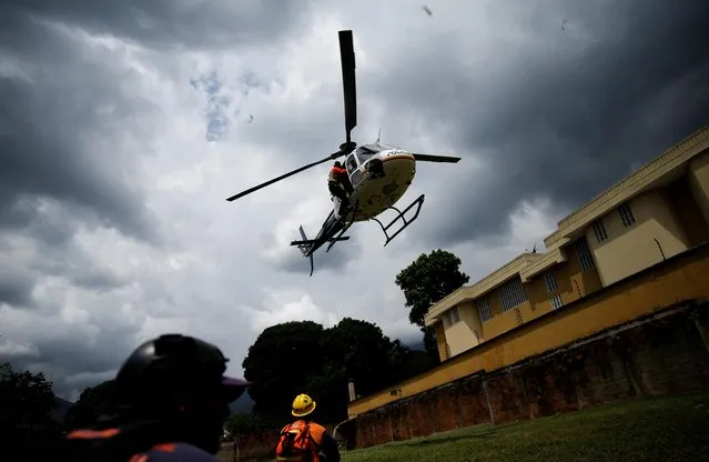 A helicopter flies over as member of a rescue team looks on as they work in an area hit by devastating floods following heavy rain in the neighbourhood of Los Castanos, in Maracay, Aragua state, Venezuela on October 18, 2022. (Photo by Leonardo Fernandez Viloria/Reuters)