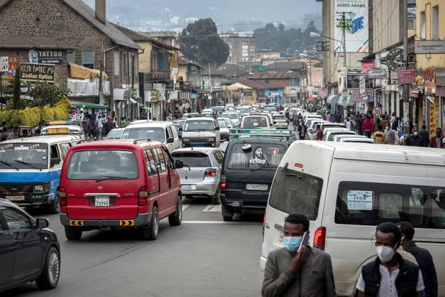 Pedestrians wear face masks to curb the spread of the coronavirus as traffic fills a street in Addis Ababa, Ethiopia Friday, July 17, 2020. (Photo by Mulugeta Ayene/AP Photo)