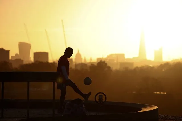 A person films himself doing kick-ups with a football during sunrise on Primrose Hill in London, Britain on November 25, 2022. (Photo by Henry Nicholls/Reuters)