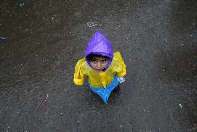 A migrant child stands on a muddy road near the border line between Serbia and Croatia, near the village of Berkasovo, about 100 km west from Belgrade, Serbia, Tuesday, September 29, 2015. Refugees from countries such as Syria, Iraq and Eritrea are used to warm climate without sudden weather changes. (Photo by Darko Vojinovic/AP Photo)