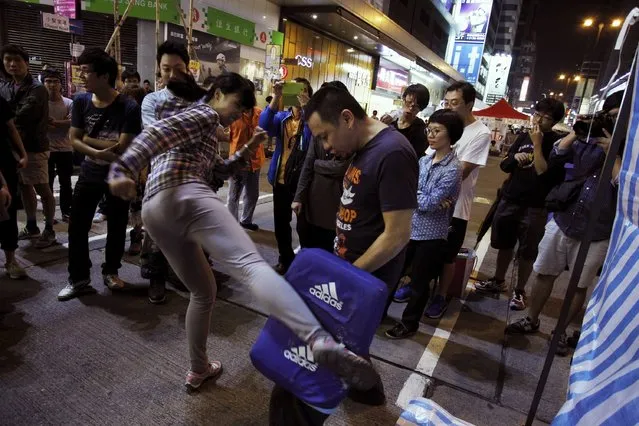 People watch a pro-democracy protester practice her kicking on a main road blocked by them as part of the Occupy Central civil disobedience movement at Mongkok shopping district in Hong Kong November 2, 2014. (Photo by Liau Chung-ren/Reuters)