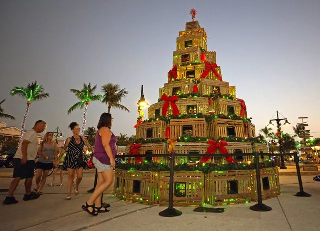 In this photo provided by the Florida Keys News Bureau, people walk past a stylized Christmas tree created from lobster traps Wednesday, December 14, 2022, in Key West, Fla. The display is one of several nautically themed Christmas icons that may be viewed along the Harbor Walk of Lights at the Key West Historic Seaport during Key West Holiday Fest, an annual island-wide celebration of the season that is to continue through New Year's Eve. (Photo by Carol Tedesco/Florida Keys News Bureau via AP Photo)