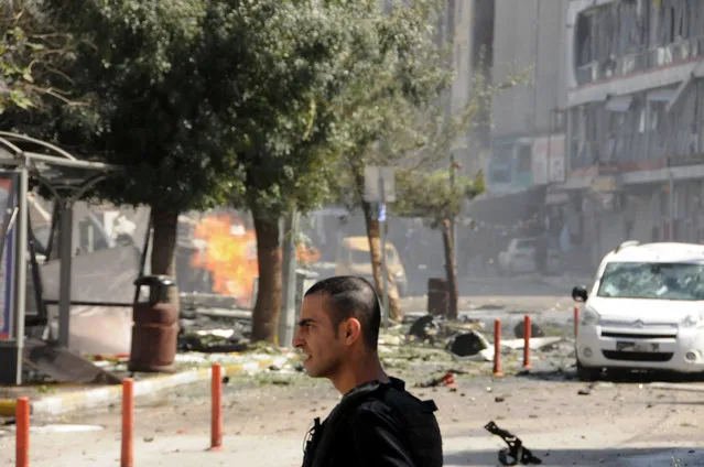 A security member stands after a car bomb attack in the city center of Van, eastern Turkey, Monday, September 12, 2016. Turkey's state-run Anadolu news agency says an explosion near the ruling party headquarters and the governor's office in the eastern province of Van has left several wounded. The explosion occurred Monday morning on the first day of Eid al-Adha, an Islamic holiday. (Photo by DHA via AP Photo)