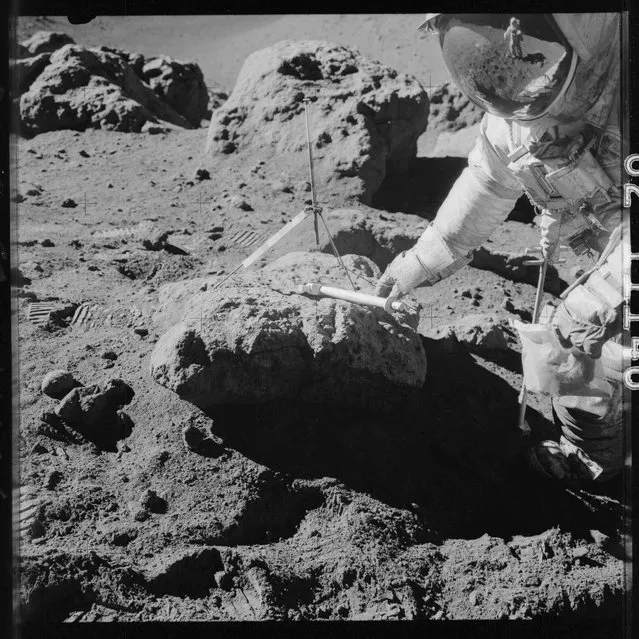 Apollo 15 commander Dave Scott takes samples at the boulder on the rim of Hadley Rille during the Apollo 15 mission in this July 1971 NASA handout photo. Astronaut James B. Irwin, lunar module pilot, can be seen in the reflection in Scott's visor. (Photo by Reuters/NASA)