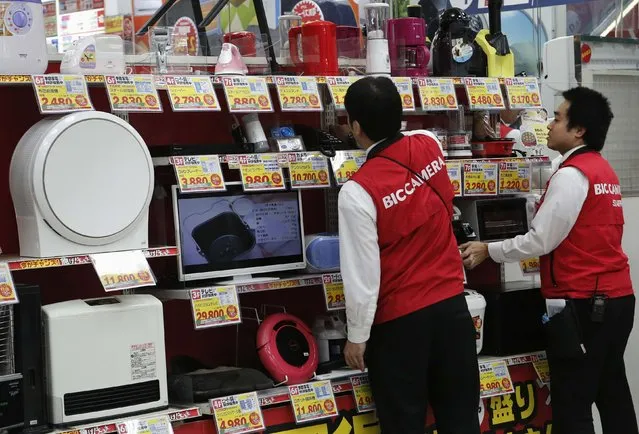 Staff clean products as they close their electronics retail store in Tokyo November 18, 201. (Photo by Yuya Shino/Reuters)
