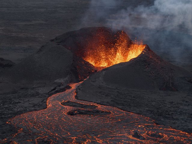 A lava flow is seen at the base of the crater, background, which is still very active after a volcanic eruption around 6km north of Grindavik on the Reykjanes Peninsula, in Iceland, Wednesday, July 23, 2025. (Photo by Marco di Marco/AP Photo)