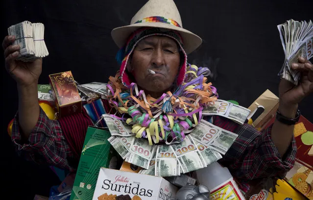 In this February 3, 2018 photo, Alberto Macias Rios, dressed as “Ekeko”, the god of prosperity and the central figure of the Alasita Fair, holds fake money as he poses for a portrait in La Paz, Bolivia. Macias, 65, says his low stature helps him pull off the Ekeko personality, which he's proud and happy to emulate. Macias competed in this year's Ekeko costume competition. (Photo by Juan Karita/AP Photo)