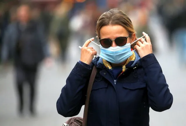 A woman adjusts her protective face mask as she walks along a street amid the outbreak of the coronavirus disease (COVID-19) in Kyiv, Ukraine on October 22, 2020. (Photo by Valentyn Ogirenko/Reuters)