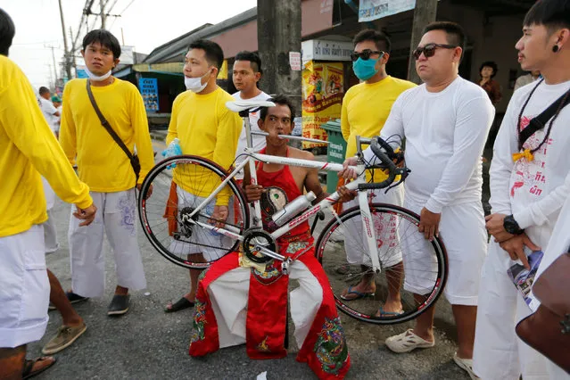 A devotee of the Chinese Samkong Shrine walks with a bike pierced on his mouth during a procession celebrating the annual vegetarian festival in Phuket, Thailand October 4, 2016. (Photo by Jorge Silva/Reuters)