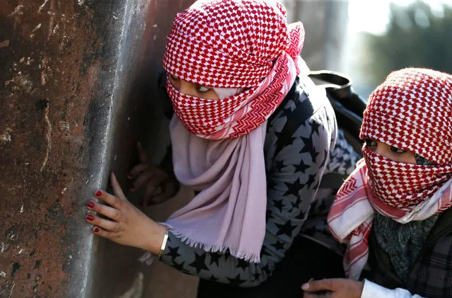 Masked Palestinian demonstrators hide behind a metal plate during clashes with Israeli soldiers on March 12, 2018 in the West Bank town of Birzeit, near Ramallah, following a protest by students of the Birzeit University against the arrest of the the head of Palestinian student council by an Israeli undercover commando. (Photo by Abbas Momani/AFP Photo)