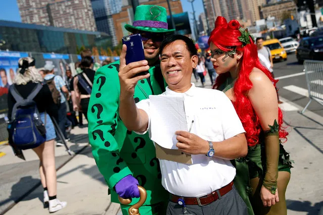 A man takes a selfie with David Gonzalez, dressed as the Riddler, and Chloe Cofresi, dressed as Poison Ivy, outside New York Comic Con in New York, U.S., October 6, 2016. (Photo by Shannon Stapleton/Reuters)