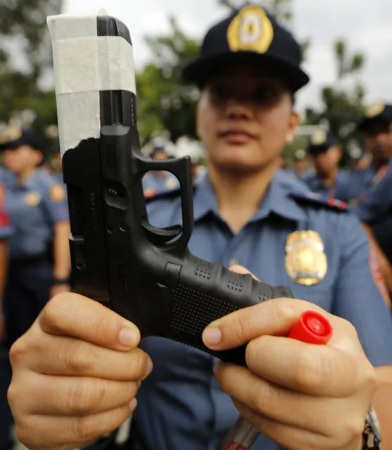 A Lady officer of the Philippine National Police force show the taped muzzle of her gun at a police camp in Taguig City, south of Manila, Philippines, 22 December 2014. Law enforcement units all over the country held a ceremonial taping of firearms as a counter measure against cases of indiscriminate firing and illegal discharge of service weapons during the upcoming Christmas and New Year celebrations. (Photo by Francis R. Malasig/EPA)