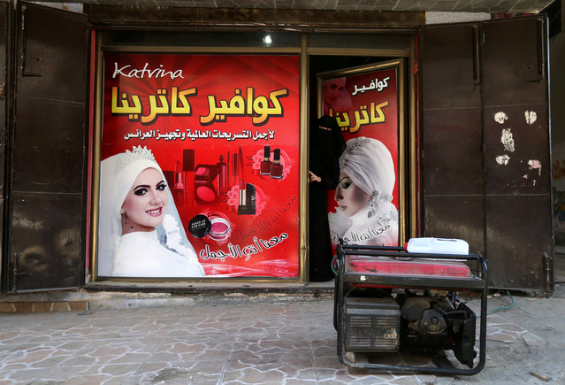 A Palestinian woman looks out of a hairstyle salon as a generator is seen outside in the southern Gaza Strip January 8, 2018. (Photo by Ibraheem Abu Mustafa/Reuters)