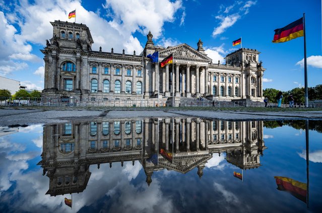 The Reichstag building, which houses Germany's lower house of parliament (Bundestag), is reflected in a puddle after a downpour in Berlin on August 4, 2025. (Photo by John MacDougall/AFP Photo)