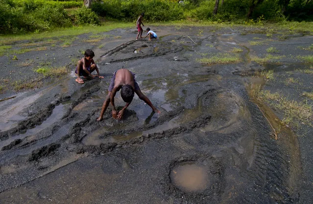In this September 13, 2014 photo, children play on a farmland destroyed by asbestos sediments in Roro, India. (Photo by Saurabh Das/AP Photo)
