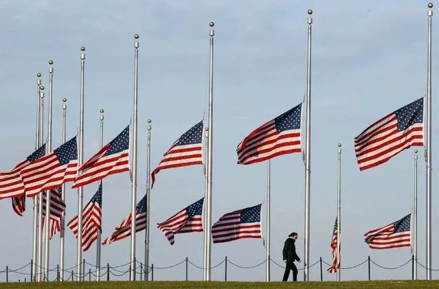 A woman walks under flags flying at half staff at the Washington Monument on the National Mall in Washington November 17, 2015.  U.S. President Barack Obama issued a proclamation ordering flags to fly at half staff as a mark of respect for victims of the Paris attacks. (Photo by Kevin Lamarque/Reuters)