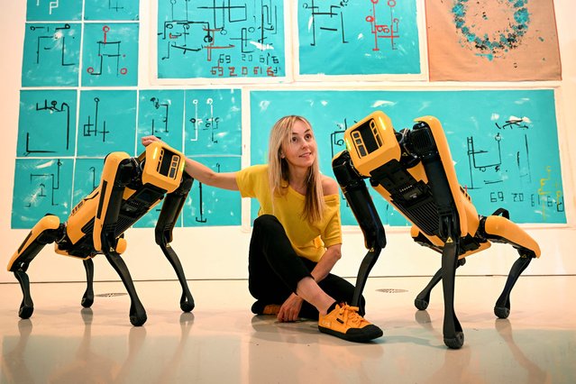 Polish artist Agnieszka Pilat poses with the artwork of her robot painting dogs – Basia Spot and Bunny Spot – who have become artists painting on canvases with their paws, at the launch of the National Gallery of Victoria (NGV) Triennial 2023 in Melbourne on April 5, 2023. Pilat works with the Boston Dynamics dogs, training them to paint autonomously through AI technology individually and collaboratively, and will be part of more than 100 local and international artists, designers and collectives presenting at the exhibition opening in December. (Photo by William West/AFP Photo)