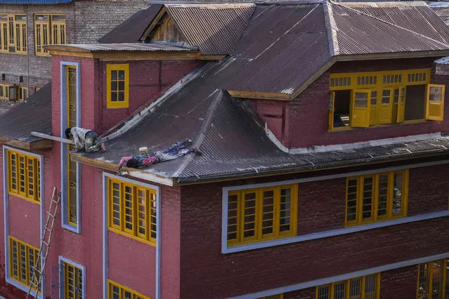 Workers paint the rooftop of a residential house in Srinagar, Indian controlled Kashmir, Monday, May 15, 2023. (Photo by Mukhtar Khan/AP Photo)