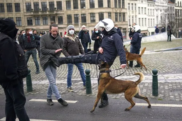 A police officer kicks a protesterduring an unauthorised demonstration against COVID-19 restrictive measures in Brussels, Sunday, January 31, 2021. According to Belgian media around 200 people have been arrested for trying to join a protest against restrictive measures implemented in the country in order to fight the virus, such as a 10pm curfew or the closing of bars and restaurants. (Photo by Francisco Seco/AP Photo)