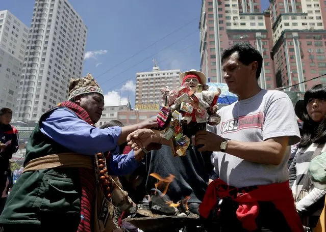 A witch doctor blesses an “Ekeko”, the god of fortune, during the “Alasitas” fair in La Paz January 24, 2015. (Photo by David Mercado/Reuters)