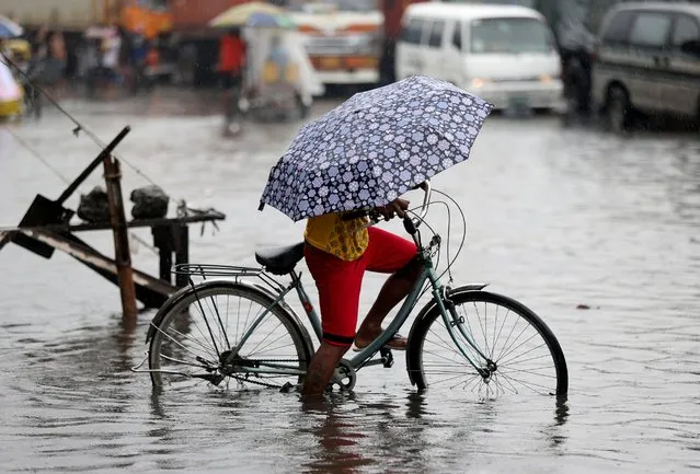 A Filipino tries to bike along a flooded street caused by heavy rains from Typhoon Melor in Manila, Philippines, December 16, 2015. Typhoon Melor left at least one person dead and wide areas without power as it crossed over the central Philippines. (Photo by Aaron Favila/AP Photo)