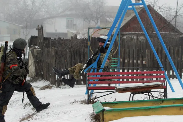 A Ukrainian serviceman of the Donbass volunteer battalion rides a swing after a clean-up operation in a village in the Lysychansk district of the Lugansk region, controlled by pro-Russian separatists, on January 28, 2015. Ukraine President Petro Poroshenko made a personal plea to Russia's Vladimir Putin and Washington threatened tougher measures on January 28 should Moscow fail to rein in separatists mounting a new offensive in the east of the ex-Soviet republic. (Photo by Anatolii Boiko/AFP Photo)