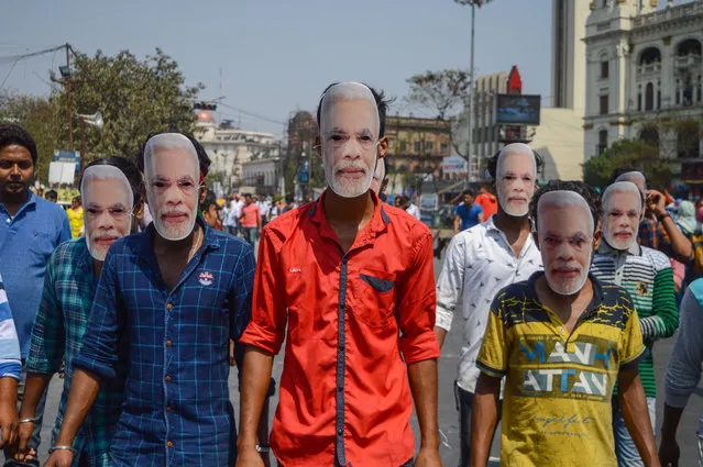 BJP supporters wear masks of the prime minister, Narendra Modi, as they make their way to a campaign meeting in Kolkata, India on March 7, 2021. (Photo by Debarchan Chatterjee/Zuma Wire/Rex Features/Shutterstock)
